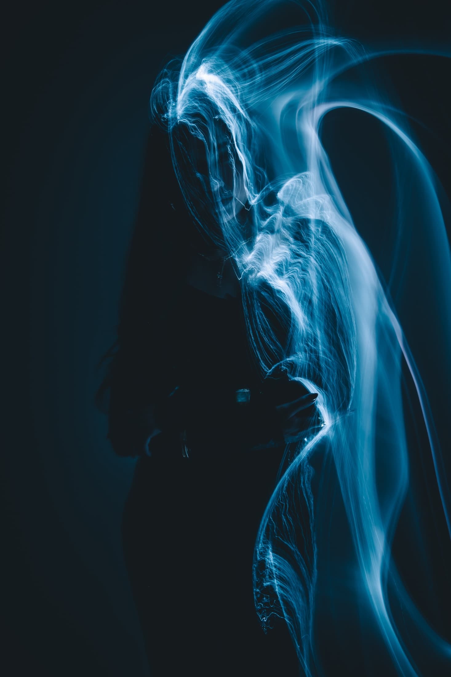 A figure traced by a pale blue ribbon of light against a dark background.