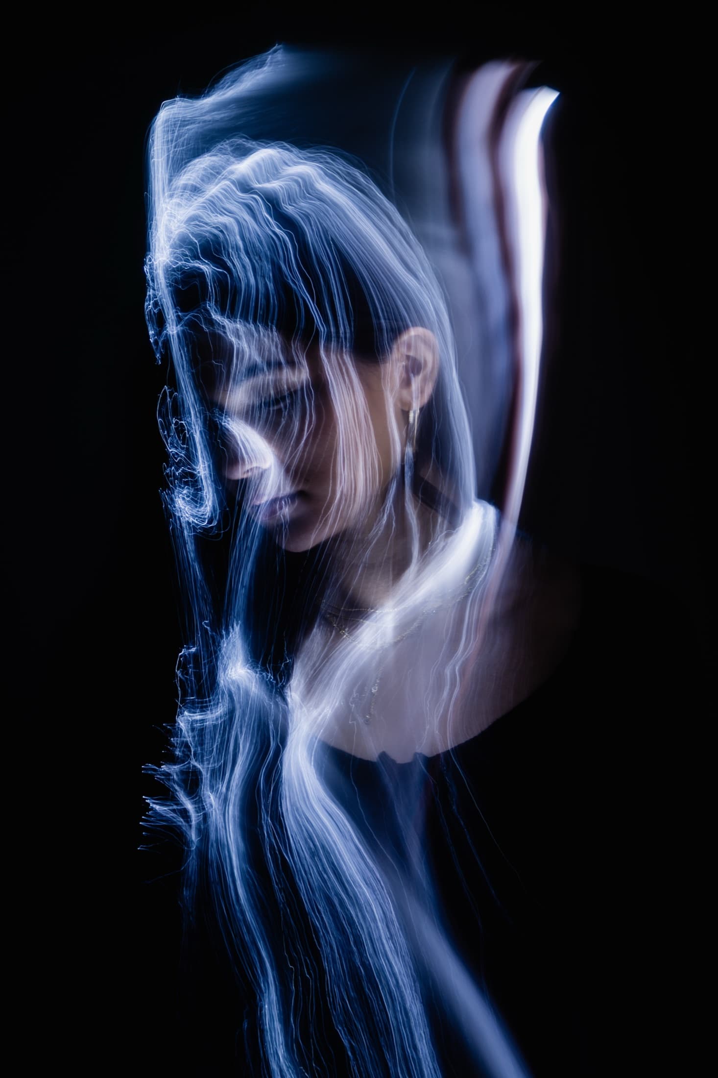 A seated portrait partially obscured by layered white light trails.