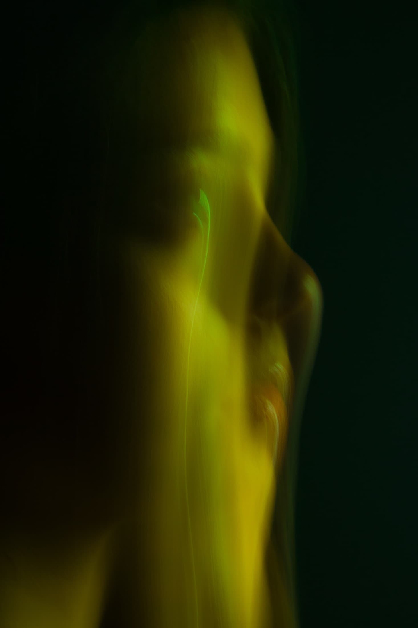 An abstract vertical form in diffused yellow-green light.