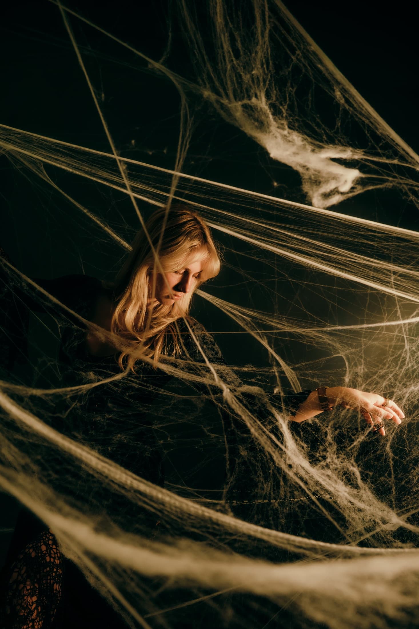 A portrait framed by dense suspended strands in a dark studio.